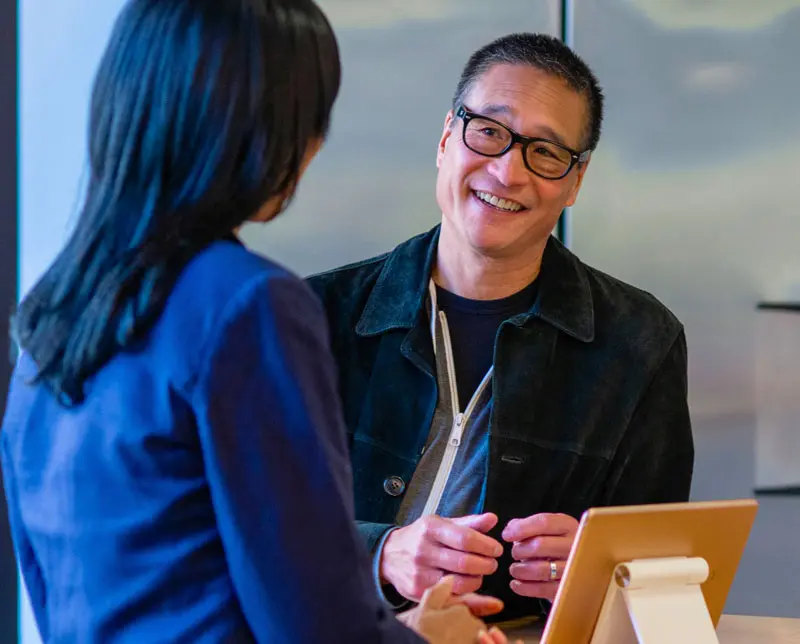 A man talks to a woman with the help of an interpreter on a tablet next to him.